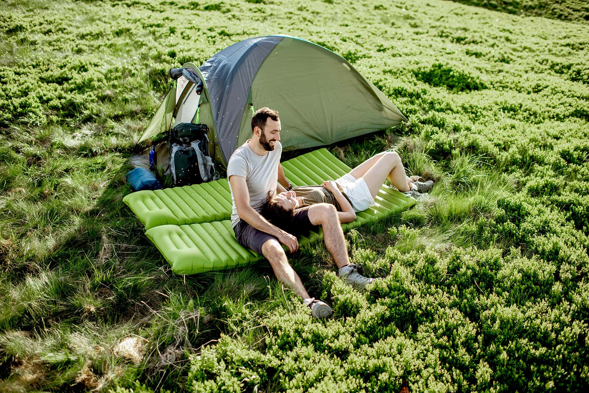 Couple camping on grass laying on Green airmattress