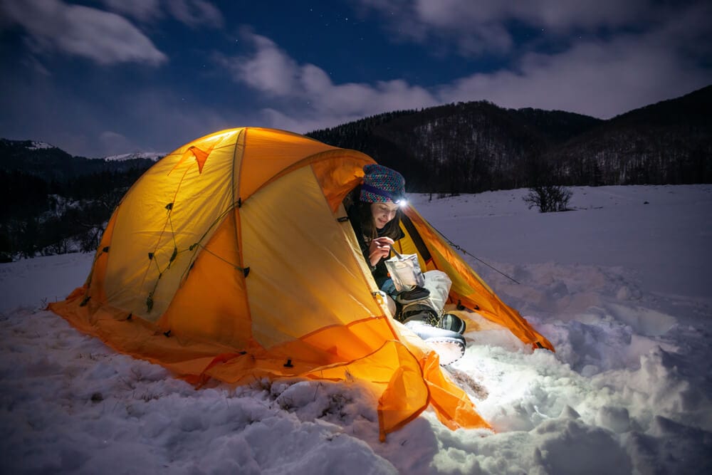 Female in hot warm tent at night in snow eating and relaxing