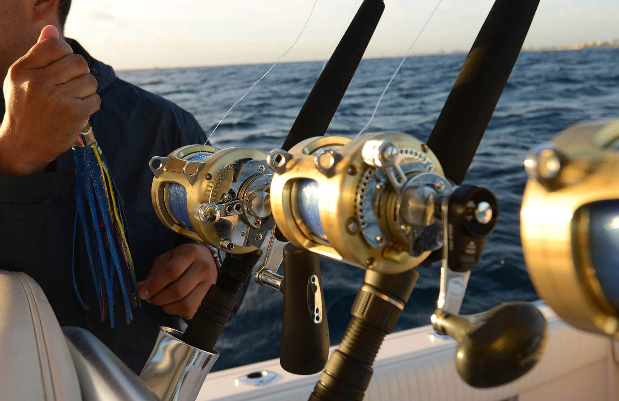 Fisherman with three gold saltwater spinning fishing reels on boat sea