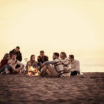 Group of young beach campers cooking on an opern fire
