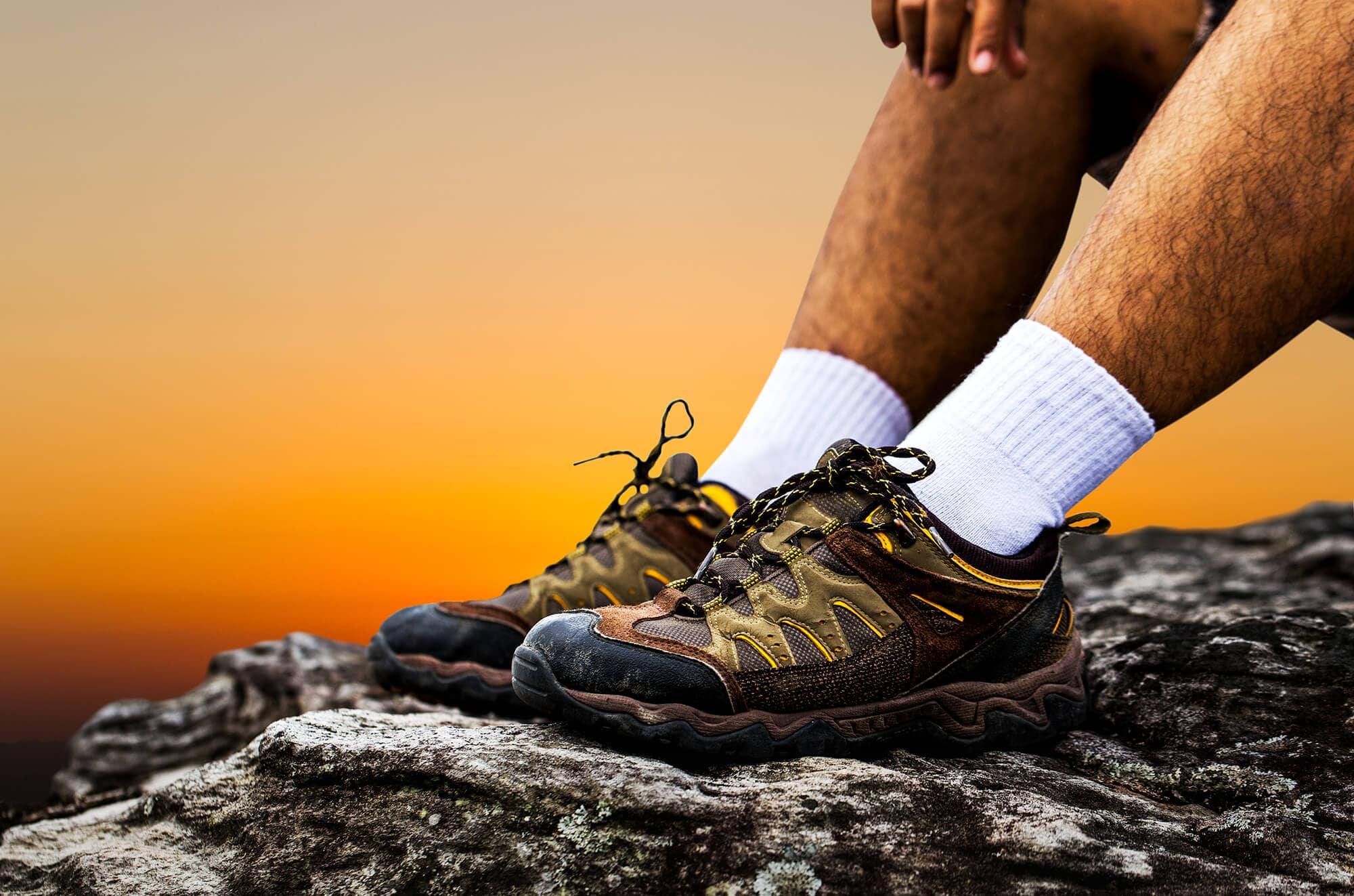 Man resting on rocky cliff with hiking boots and sock liners