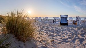 Striped Mediterranean canvas canopy chairs on white sandy beach