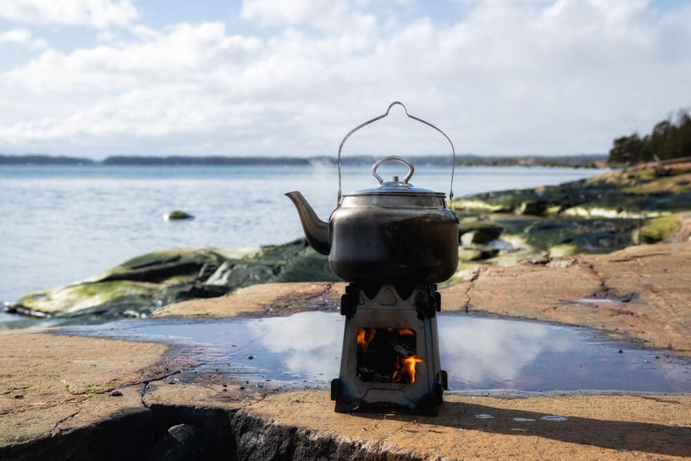 Wood burning stove boiling water during hiking break at the sea